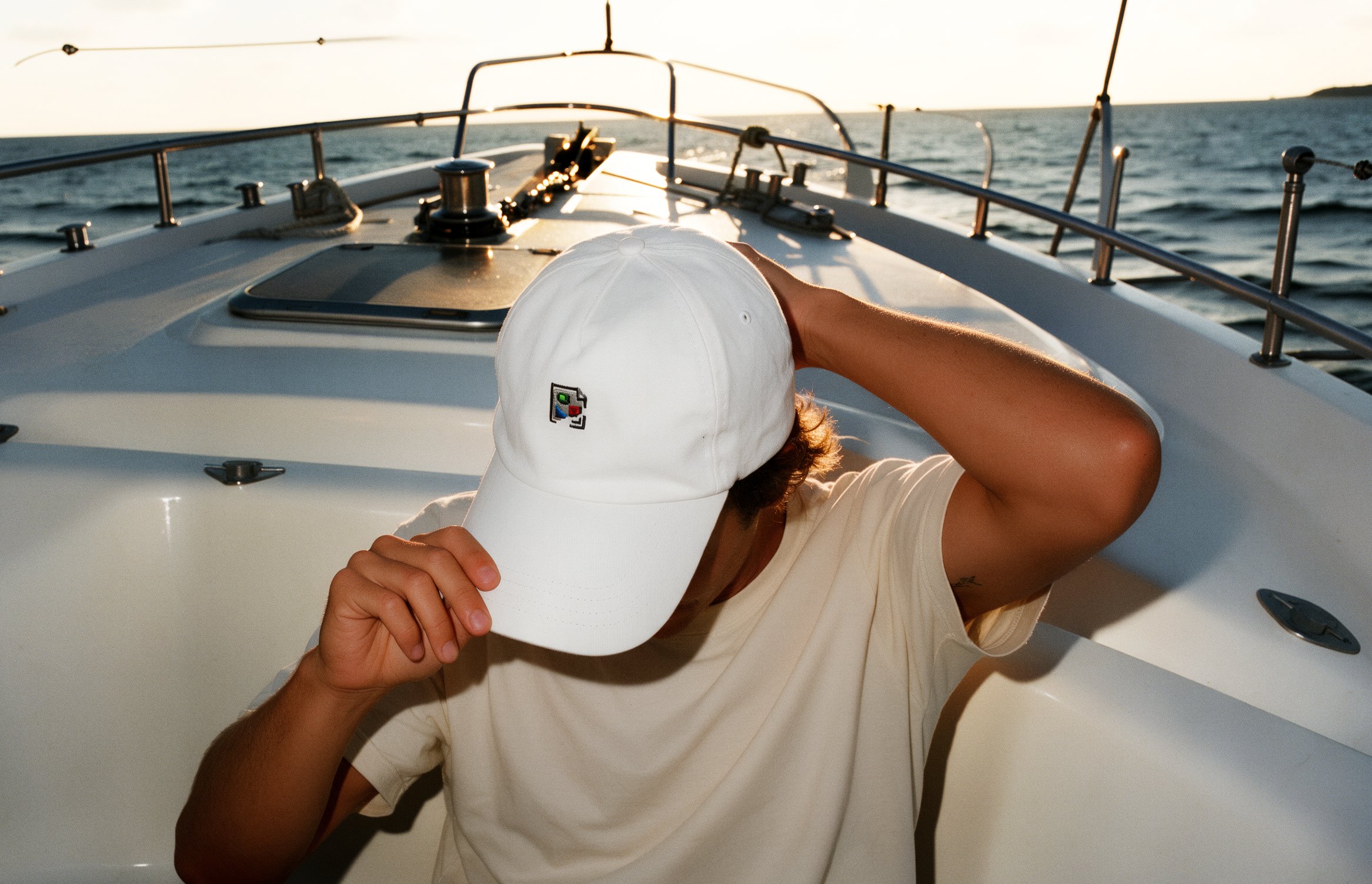 Figure wearing a white cap on the deck of a boat