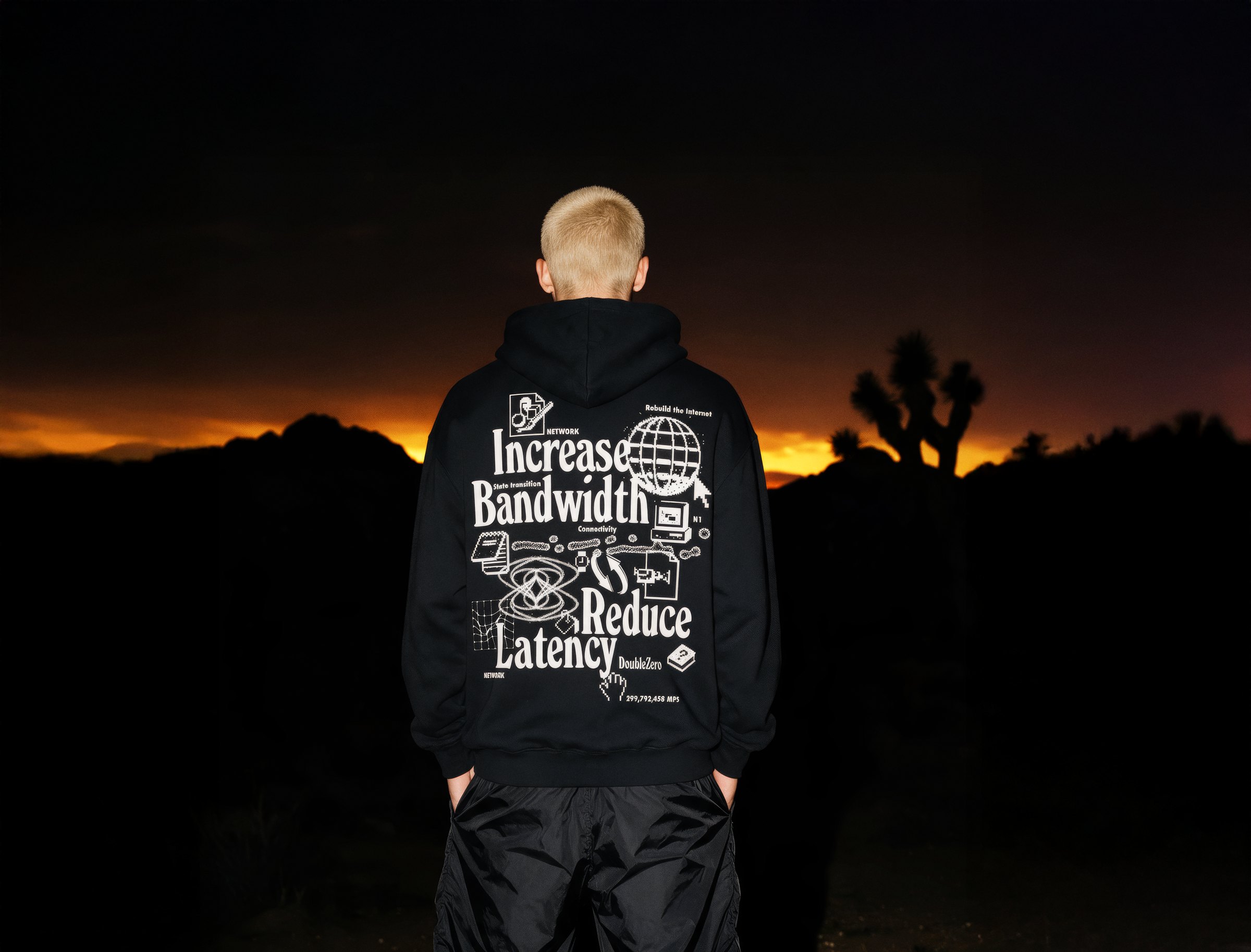 Figure wearing a black hoodie against a sunset