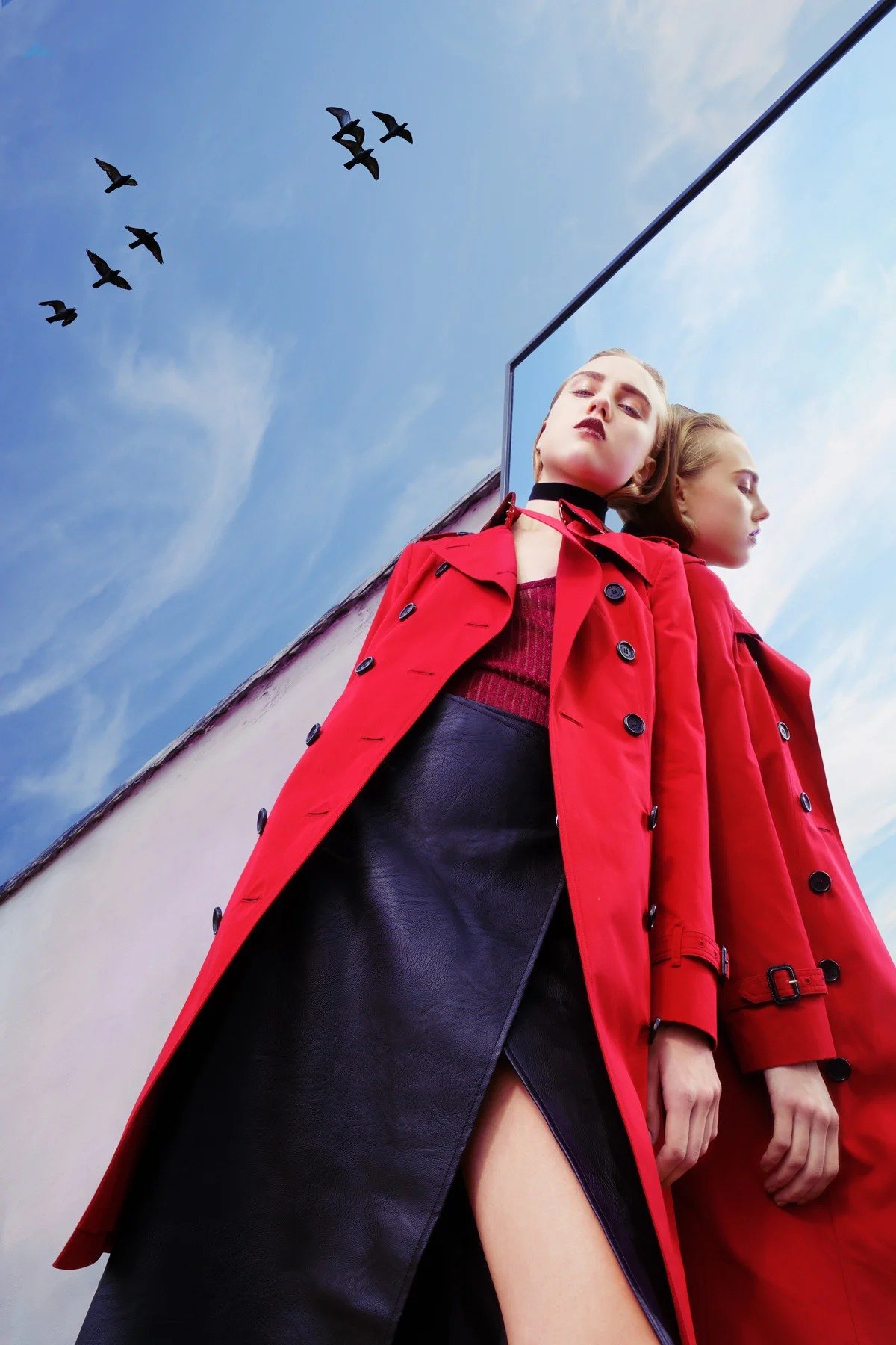 Figure in a red coat reflected against a blue sky