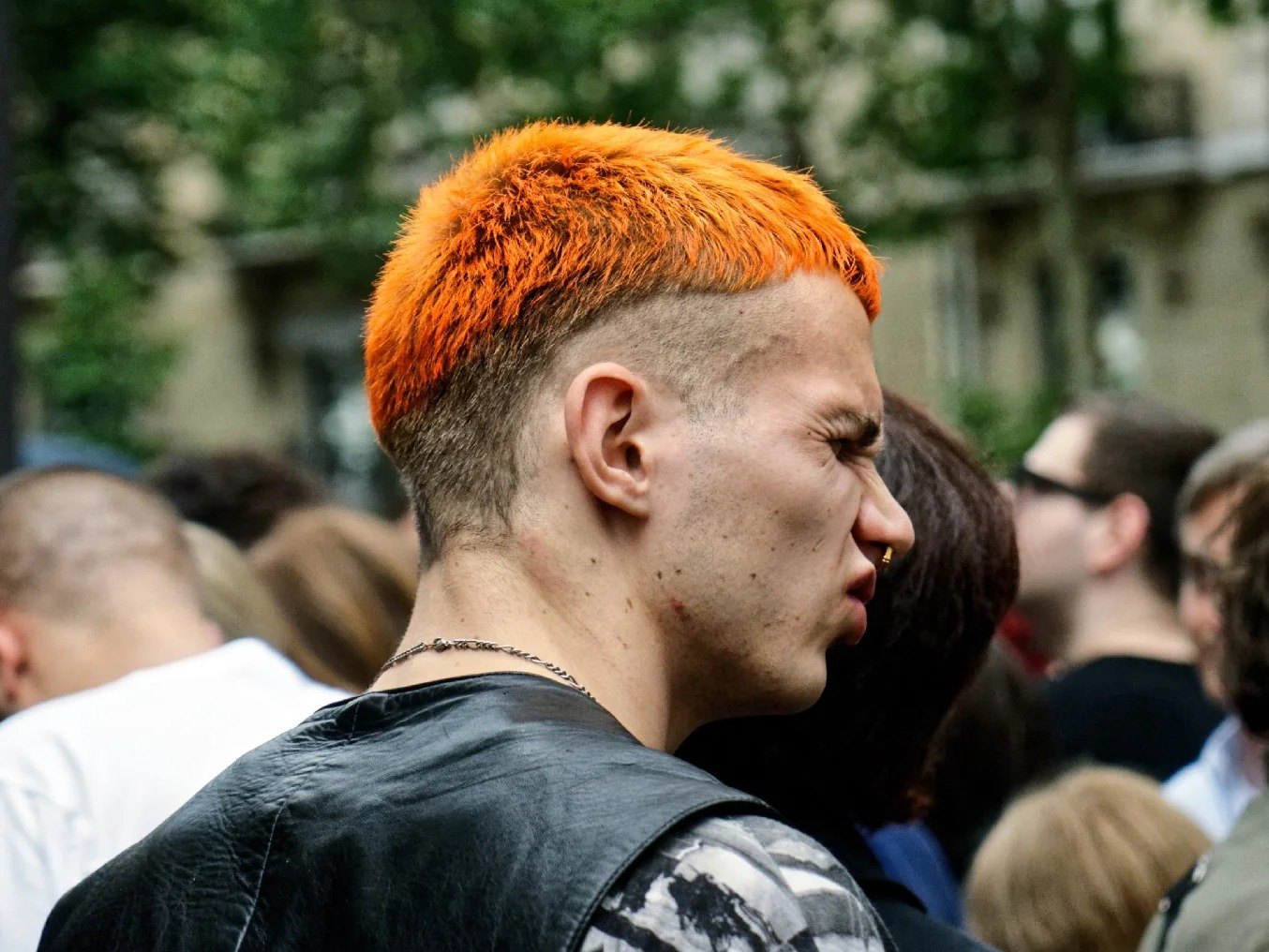 Close-up of a figure with bright orange hair in a crowd