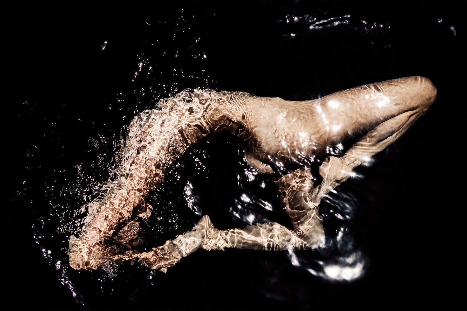 Curved figure beneath rippling water against black