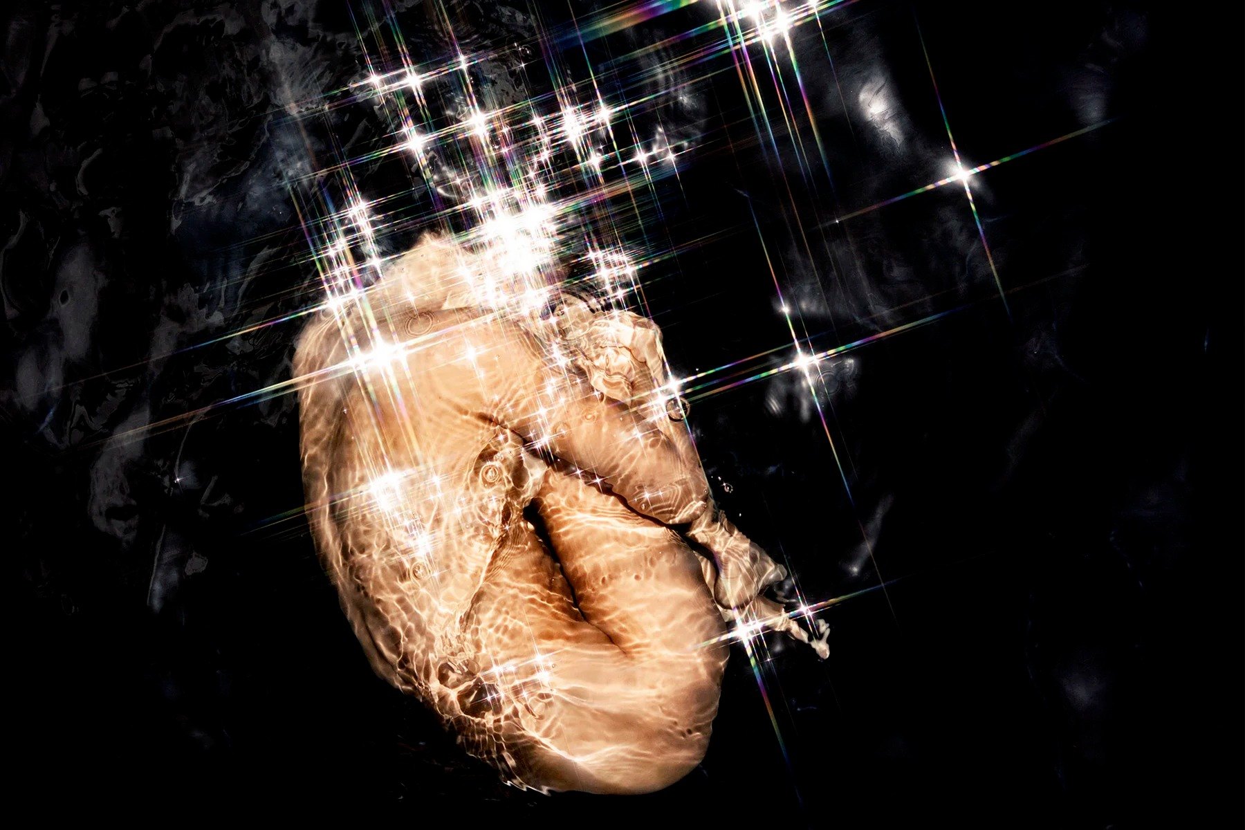 Close-up of a face beneath water with bright reflections