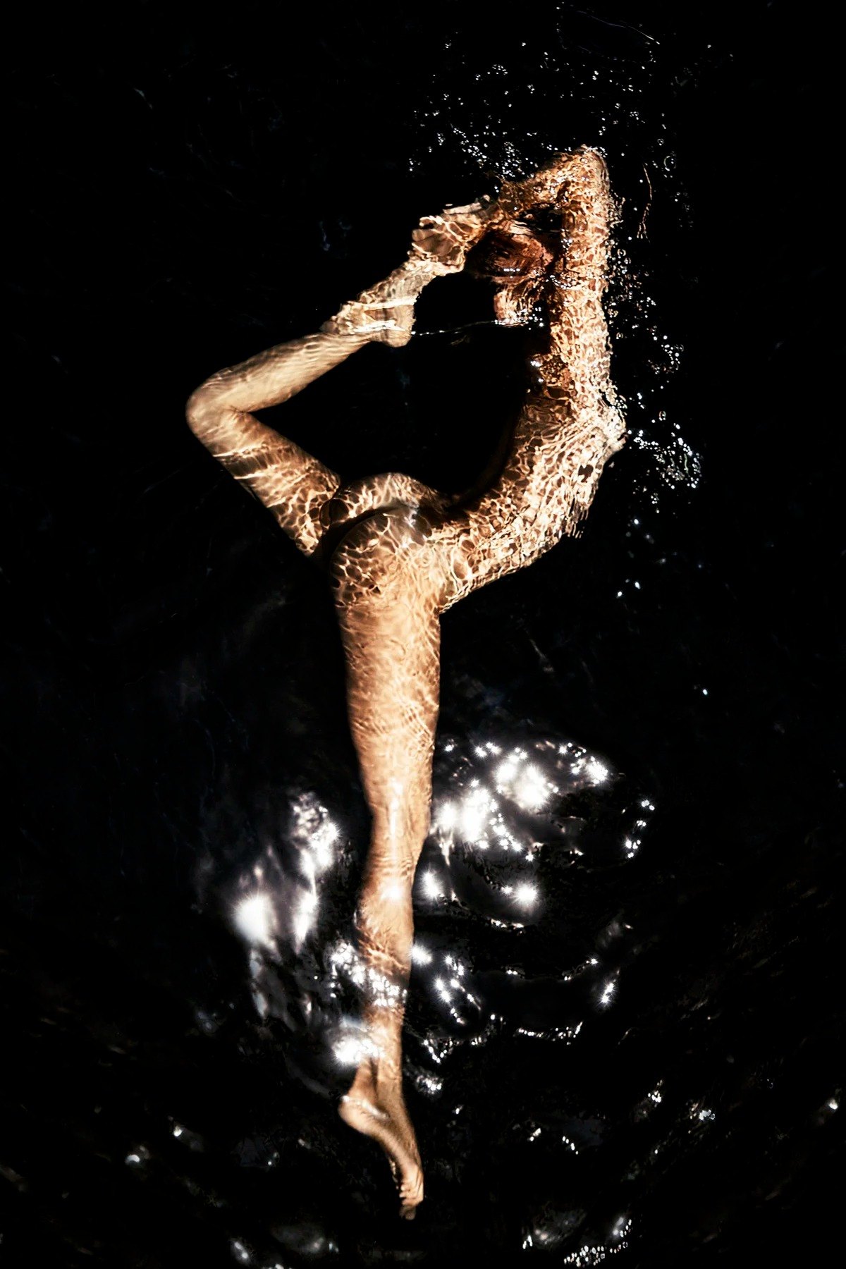 Submerged figure stretching both arms overhead