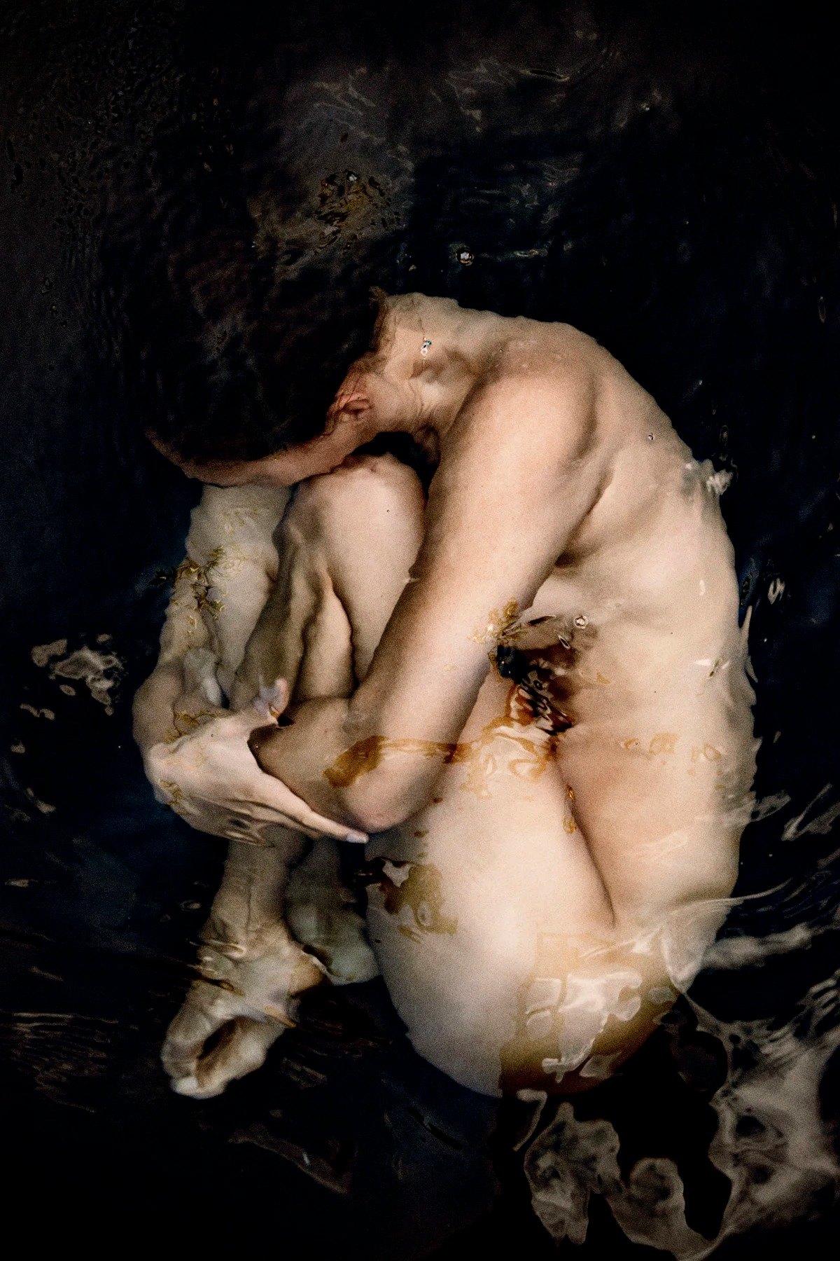 Curled figure seen through dark reflective water
