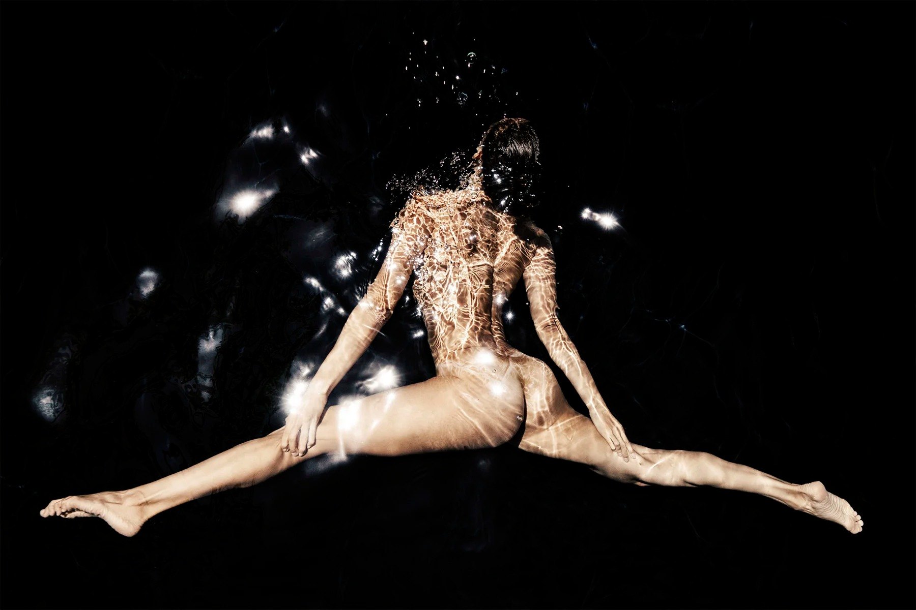 Submerged figure with limbs extended amid bubbles