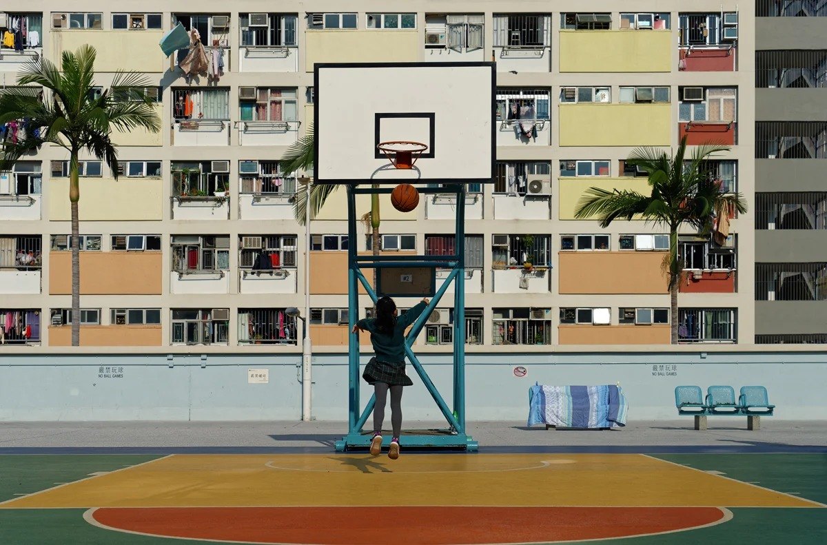 Basketball court beneath a grid of apartment windows