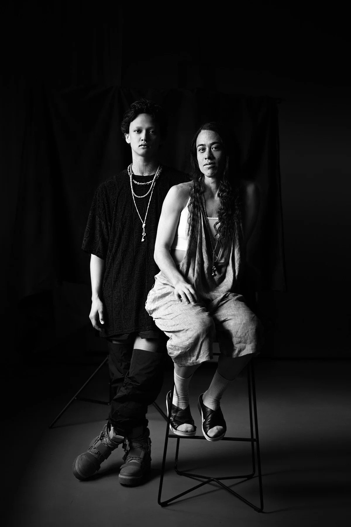 Black-and-white portrait of two figures in a dark interior