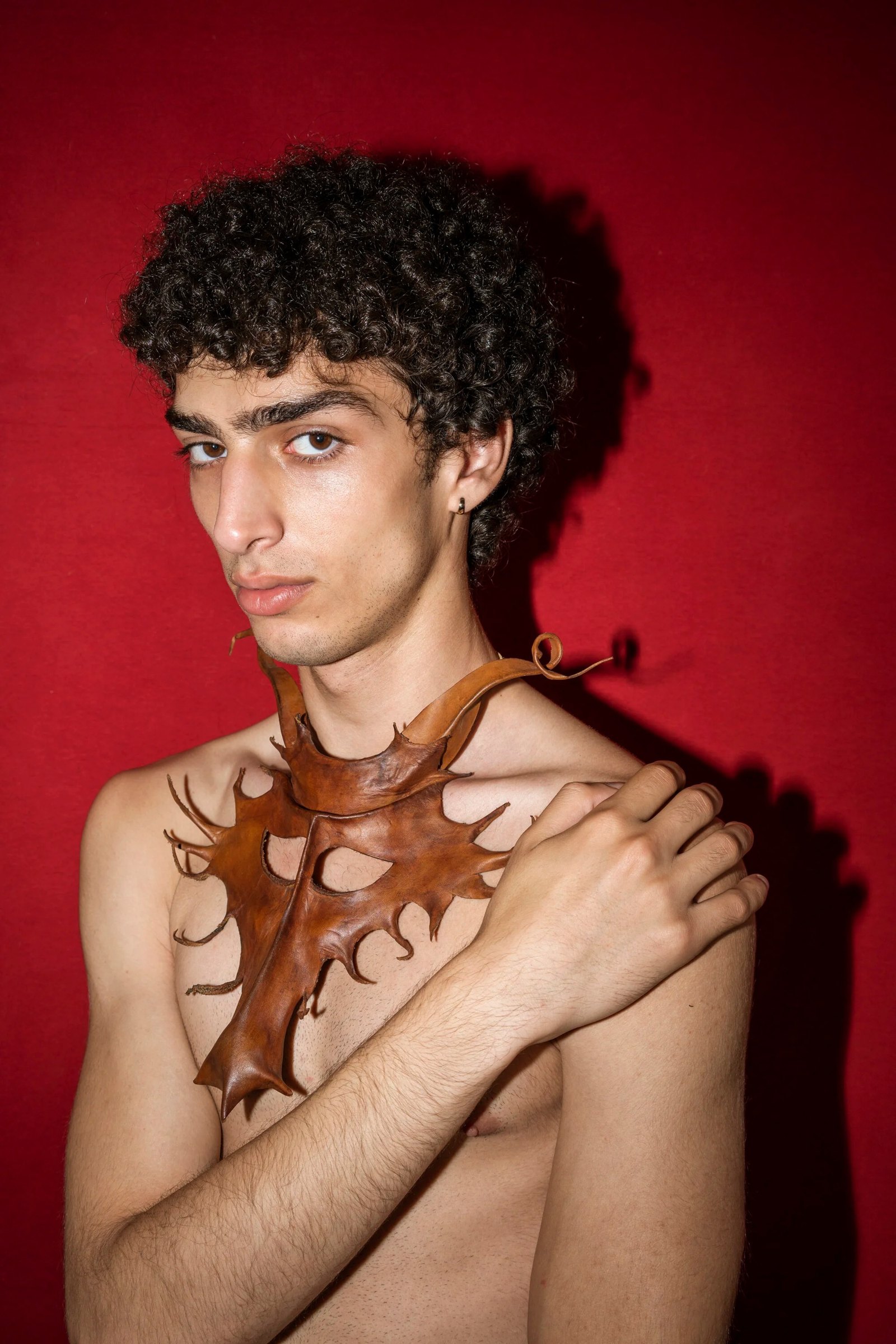 Qaher with crossed arms against a red background