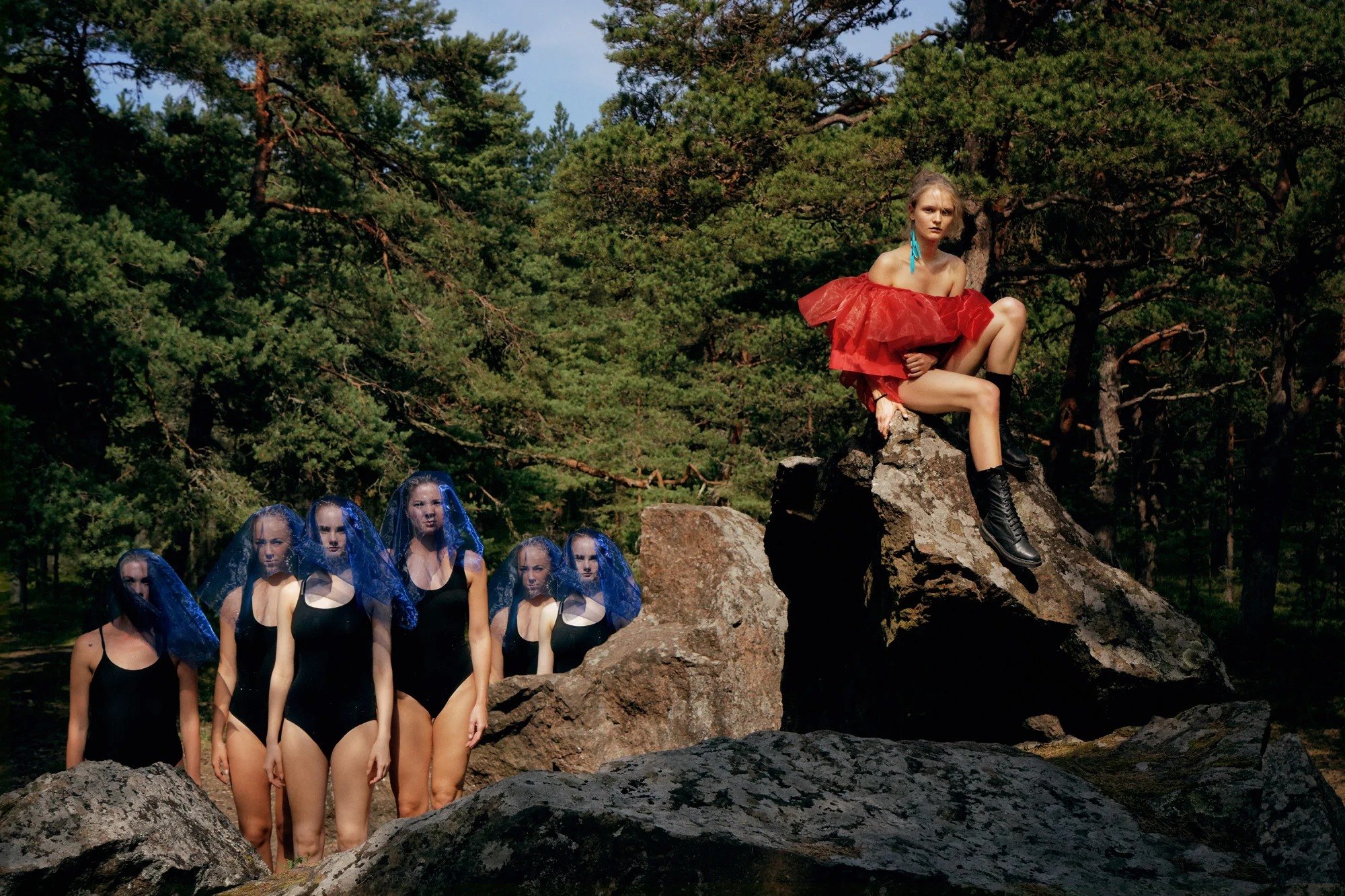 Group of figures posed on rocks at the edge of a forest